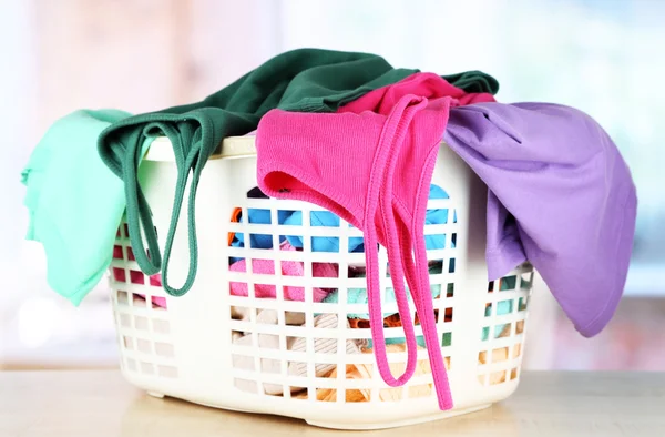 Roupas em cesta de plástico na mesa no quarto — Fotografia de Stock