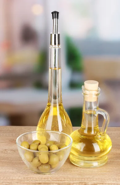 Different types of oil with olives on table in kitchen