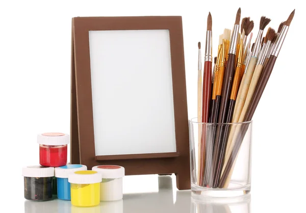 Photo frame as easel with artist's tools isolated on white — Stock Photo, Image