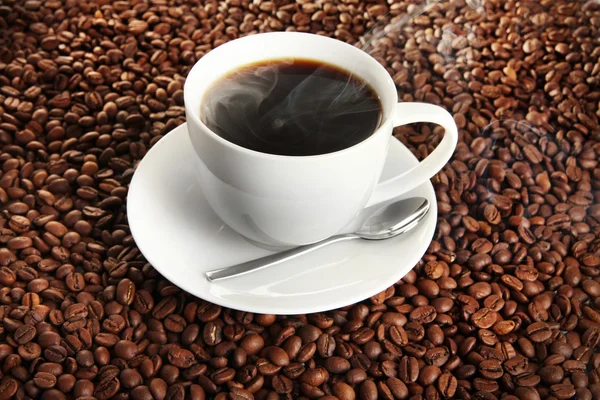 Cup of coffee on coffee beans background — Stock Photo, Image