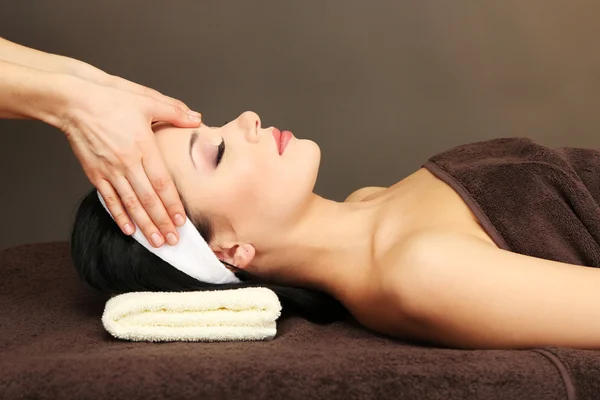 Красивая молодая женщина в спа-салоне принимает массаж головы, на темном фоне — стоковое фото