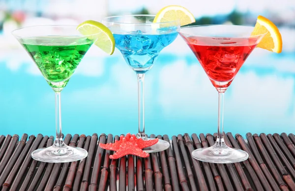 Glasses of cocktails on table near pool — Stock Photo, Image