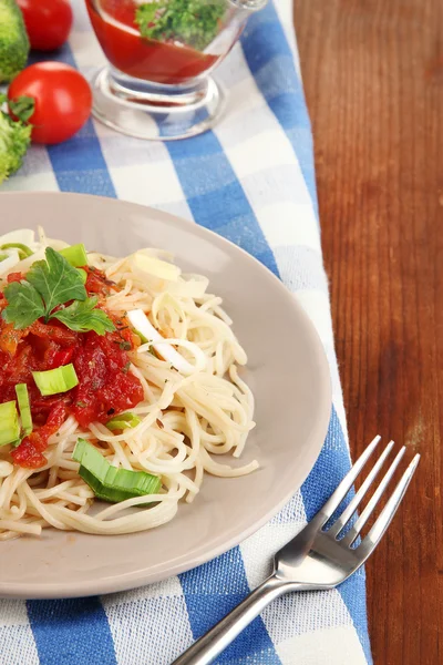 Smaczne spaghetti z sosem i warzywami na tabliczce na drewniany stół szczegół — Zdjęcie stockowe