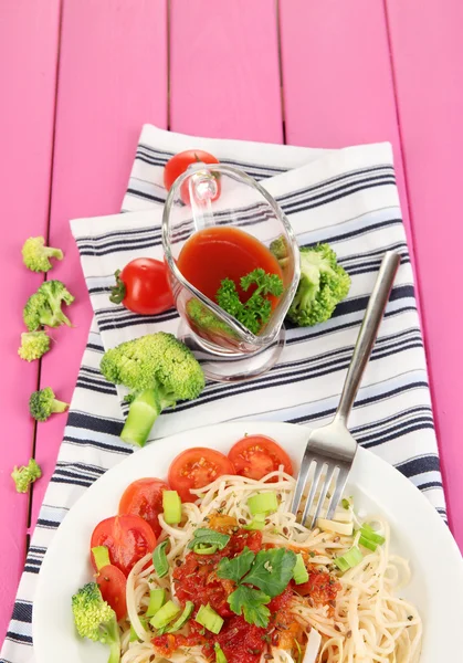 Tasty spaghetti with sauce and vegetables on plate on wooden table close-up — Stock Photo, Image