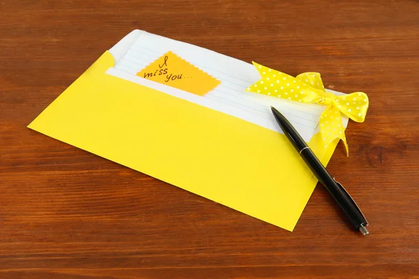 Note in envelope with pen on wooden background — Stock Photo, Image