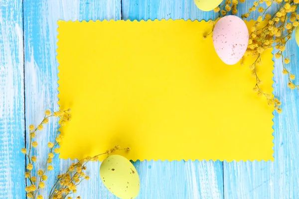 Empty card with easter eggs and mimosa flowers, on blue wooden background — Stock Photo, Image