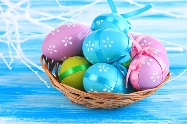 Huevos de Pascua en cesta, sobre fondo de madera azul — Foto de Stock