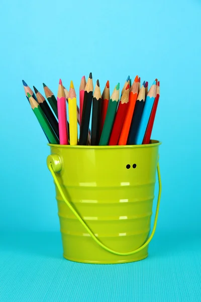 Lápices de colores en cubo sobre fondo azul — Foto de Stock