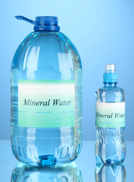 Různé lahve s vodou s popiskem na modrém pozadí — Stockfoto