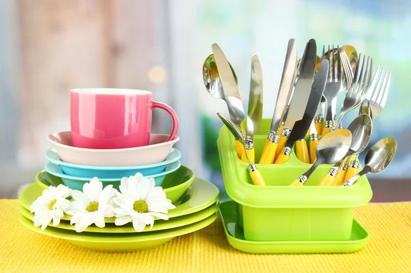 Placas, garfos, facas, colheres e outros utensílios de cozinha em guardanapo de cor, no fundo brilhante — Fotografia de Stock