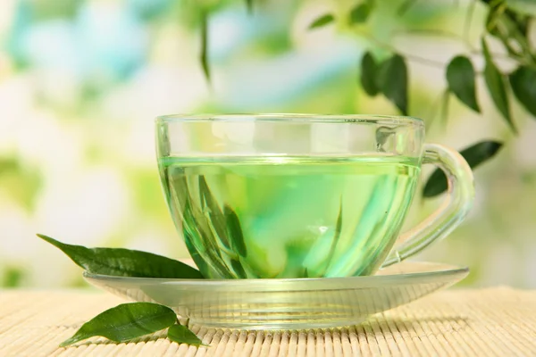 Taza transparente de té verde sobre estera de bambú, sobre fondo natural — Foto de Stock