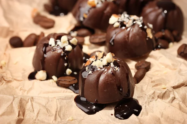 Doces de chocolate e grãos de café, sobre fundo de papel bege — Fotografia de Stock