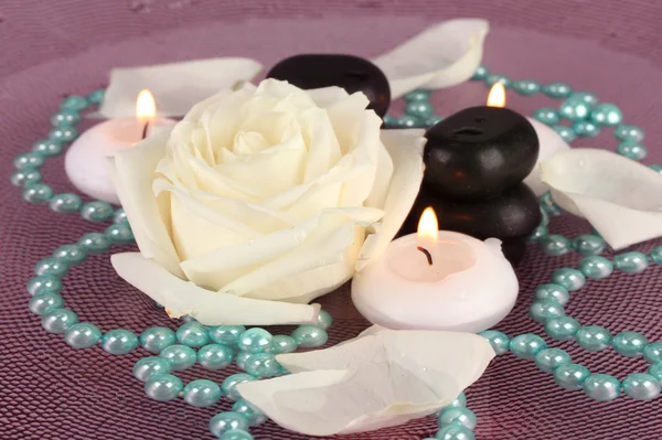 Piedras de spa con flores y velas en agua en el plato —  Fotos de Stock