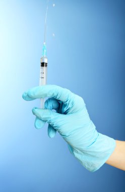 Doktor holding şırınga ile mavi arka plan üzerinde bir aşı