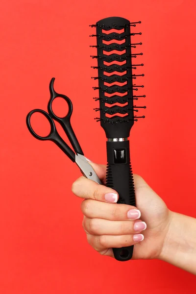 Color comb and scissors in female hand on color background — Stock Photo, Image