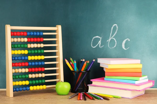 Toy abacus, books and pencils on table, on school desk background — Stock Photo, Image