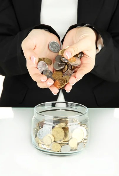 Saving, female hands putting coins into glass bottle, isolated on white — Stock Photo, Image