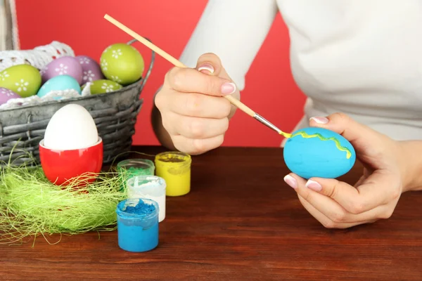 Young woman painting Easter eggs, on color background — Stock Photo, Image