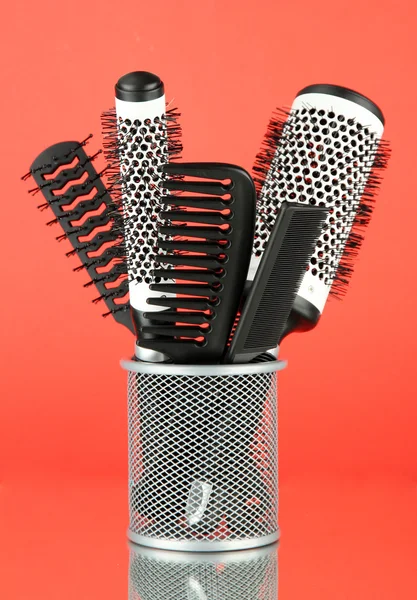 Cesta de ferro com pentes e escovas de cabelo redondas, sobre fundo de cor — Fotografia de Stock