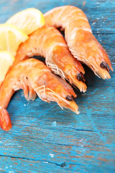 Gamberetti con limone sul tavolo di legno blu — Foto Stock