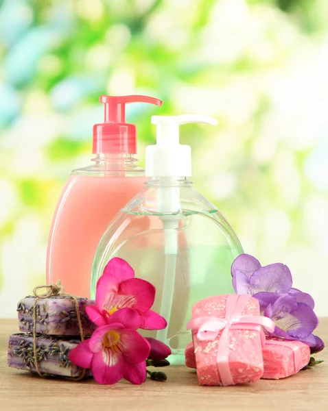 Flüssige und handgemachte Seifen auf Holztisch, auf grünem Hintergrund — Stockfoto