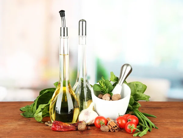 Composição de argamassa, garrafas com azeite e vinagre, e ervas verdes, sobre fundo brilhante — Fotografia de Stock