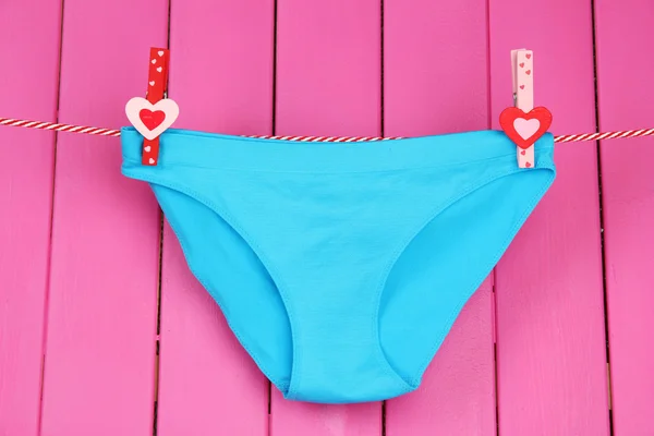 Womans panties hanging on a clothesline, on pink wooden background — Stock Photo, Image