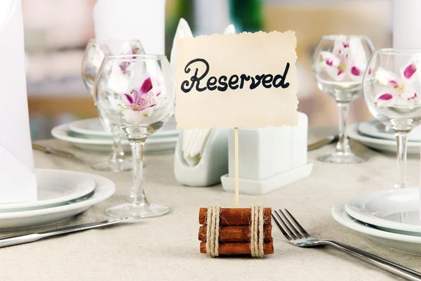 Reserved sign on restaurant table with empty dishes and glasses — Stock Photo, Image