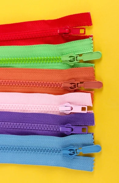 Multicolored zippers on yellow background — Stock Photo, Image