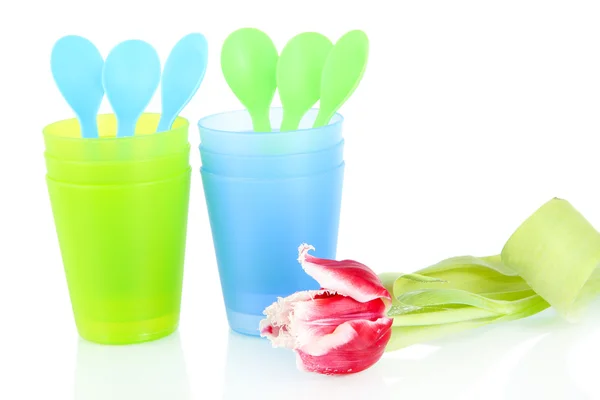 Blue and green plastic cups and spoons, pink tulip isolated on white — Stock Photo, Image