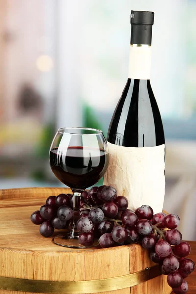 Composição de garrafa de vinho, vidro e uva, em barril de madeira, sobre fundo brilhante — Fotografia de Stock