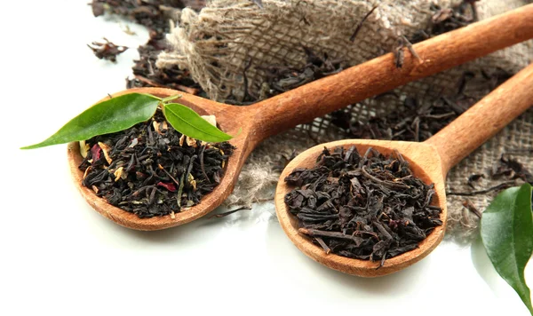 Tè secco con foglie verdi in cucchiai di legno, isolato su bianco — Foto Stock