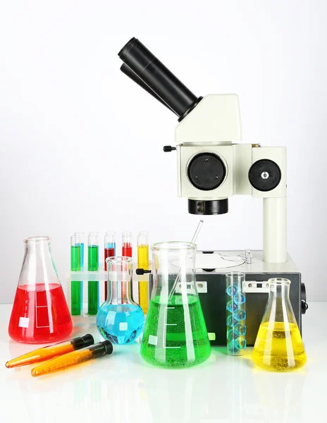 Δοκιμαστικοί σωλήνες με πολύχρωμο υγρών και μικροσκόπιο απομονωθεί σε λευκό — Φωτογραφία Αρχείου