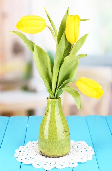 Tulipas amarelas em vaso na mesa de madeira no fundo do quarto — Fotografia de Stock