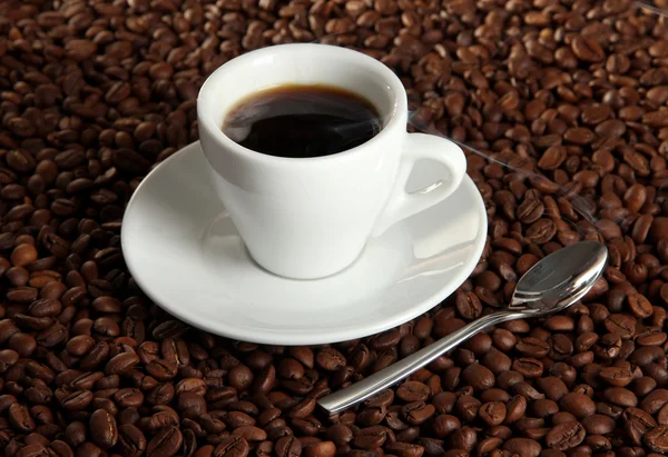 Cup of coffee on coffee beans background — Stock Photo, Image