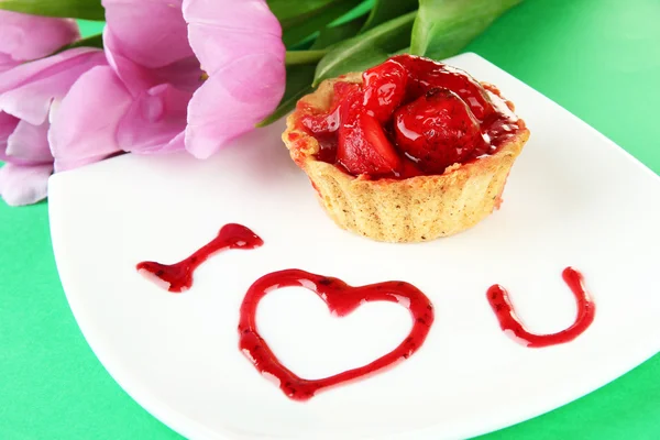 Süße Torte mit Erdbeere und Soße auf Teller, auf farbigem Hintergrund — Stockfoto