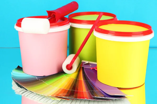 Set for painting: paint pots, paint-rollers, palette of colors on blue background — Stock Photo, Image