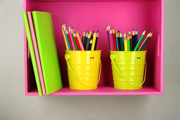 Lápis coloridos em pails na prateleira no fundo bege — Fotografia de Stock