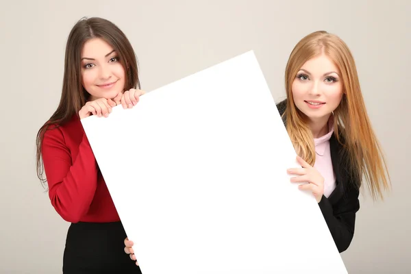 Two business women with blank form on grey background — Stock Photo, Image