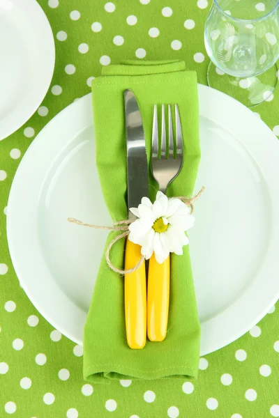 Knife and fork wrapped in napkin, on plate, on color tablecloth background — Stock Photo, Image