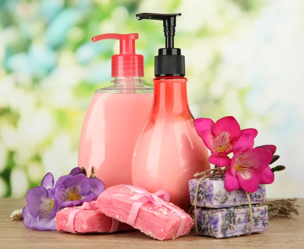 Liquid and hand-made soaps on wooden table, on green background — Stock Photo, Image