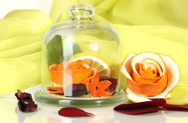Ozdobny róża z suchej skórki pomarańczowej w szklanym wazonie na tle zielonej tkaniny — Zdjęcie stockowe