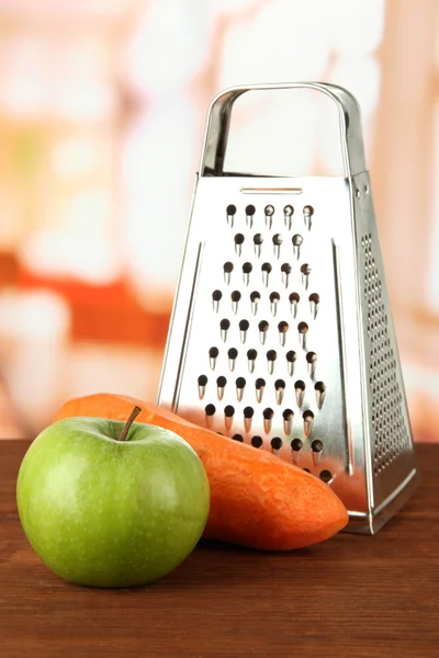 Rallador de metal y manzana, zanahoria, sobre fondo brillante — Foto de Stock