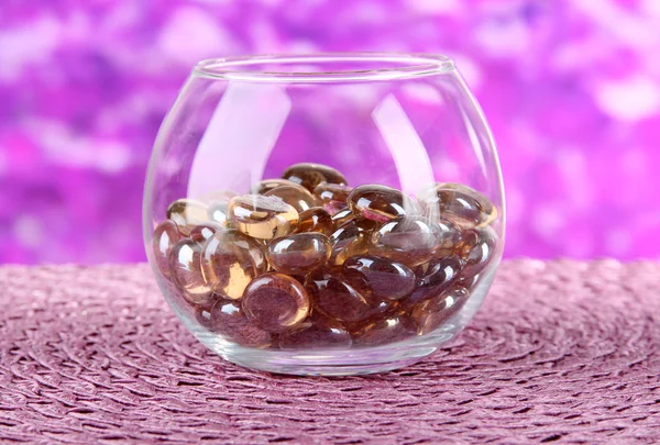 Glas met kleurrijke decoratieve stenen op lichte achtergrond — Stockfoto