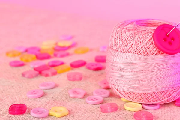 Красивые кнопки и клубок пряжи на розовом фоне — стоковое фото