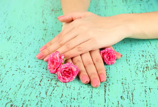 Mani donna con manicure rosa e fiori, su sfondo colore — Foto Stock