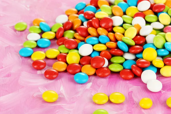Caramelos de colores sobre fondo rosa — Foto de Stock