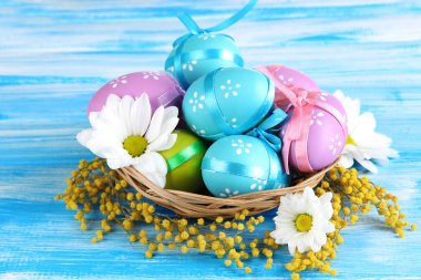 sepet ve Mimoza çiçekler, mavi ahşap zemin üzerinde Paskalya yortusu yumurta