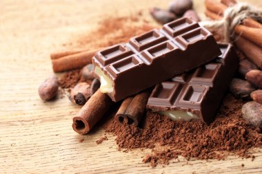 Composition of chocolate sweets, cocoa and spices on wooden background