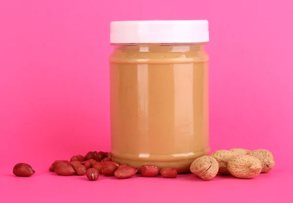 Delicious peanut butter in jar of peanut near on pink background — Stock Photo, Image